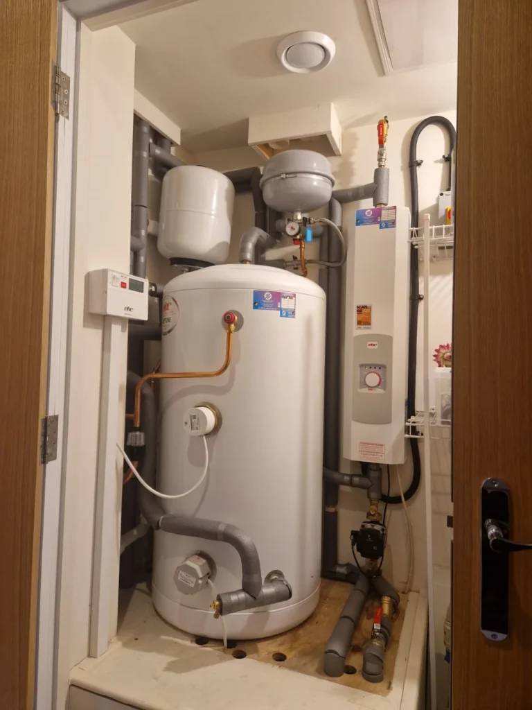 Electric boiler and cylinder installed in a plant cupboard with the door open