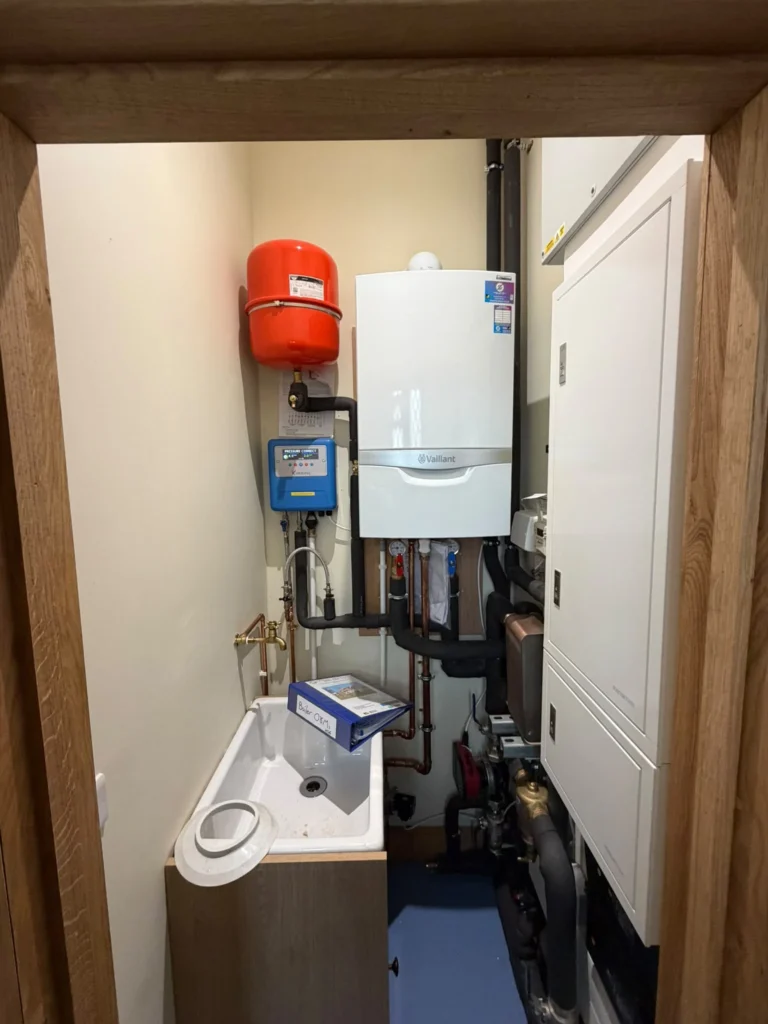 Wall-hung commercial boiler and expansion vessel installed in a compact plant cupboard