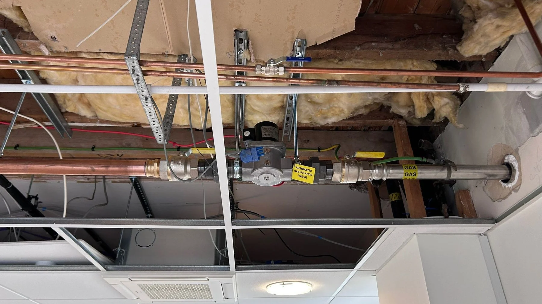 Gas pipework and isolation valve installed in a ceiling void above an office