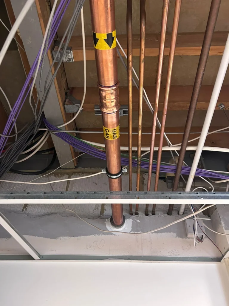 Copper gas riser and interlock wiring passing through a suspended ceiling