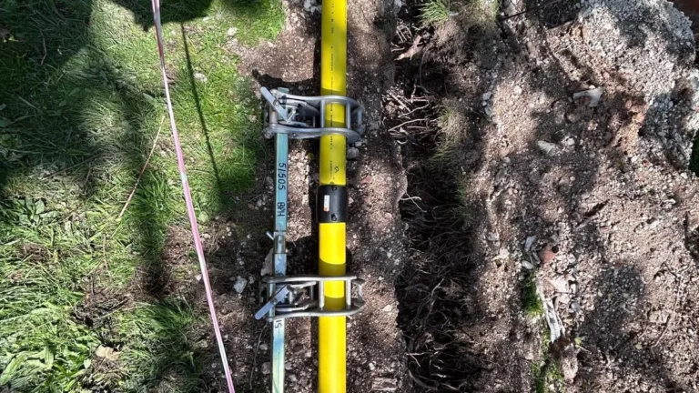 Yellow fusion welded polyethylene gas main laid in an open trench across a grass verge