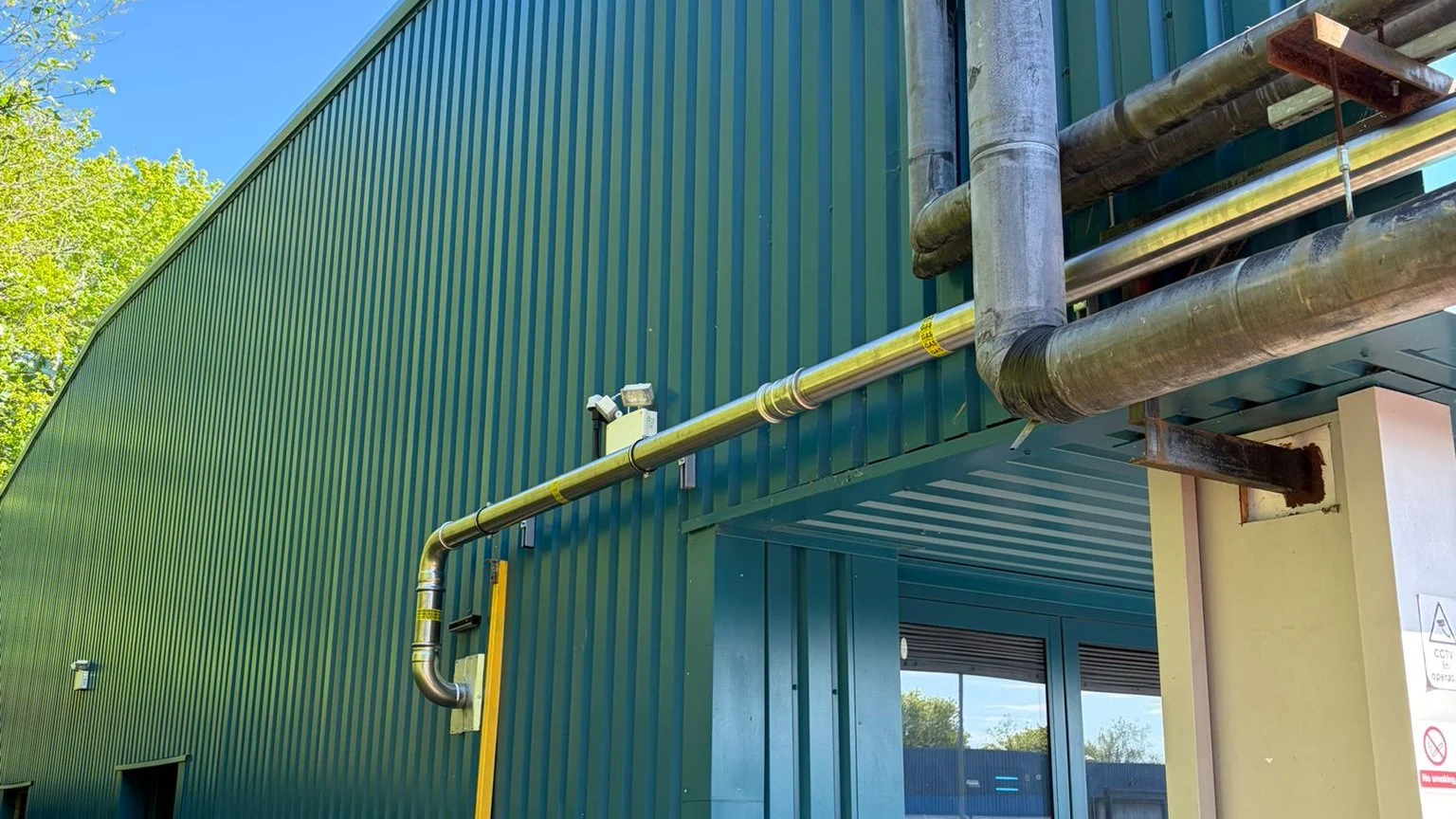 External gas supply pipework run along the elevation of a clad commercial building