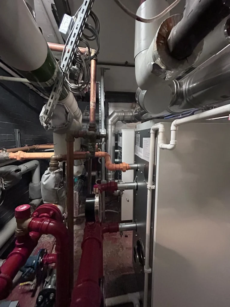 Large bore heating pipework, valves and insulated ductwork in a commercial plant room