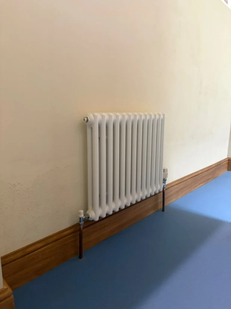 Wall-mounted column radiator installed as part of a commercial heating system