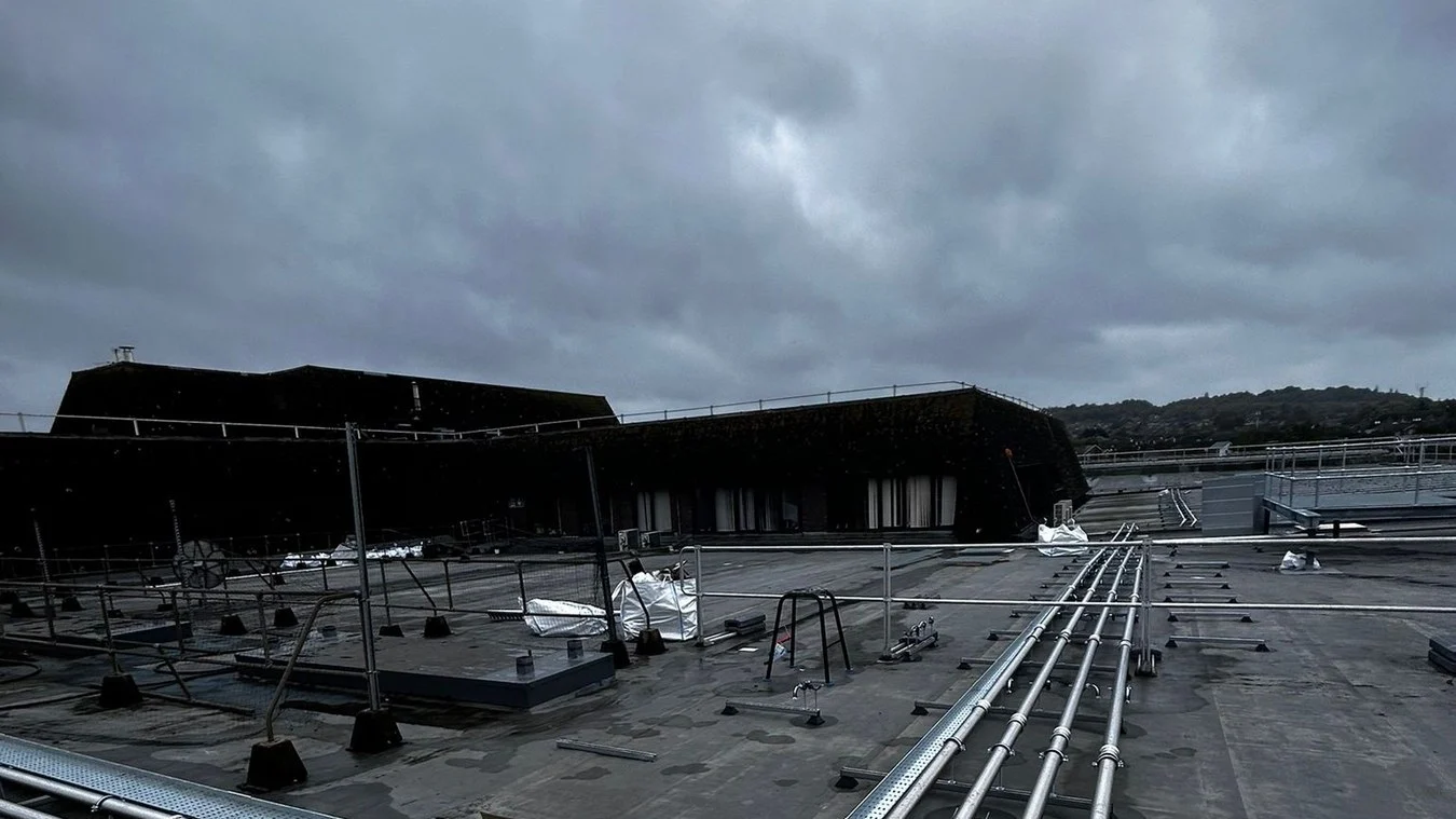 Long runs of insulated pipework on proprietary supports across a flat commercial roof