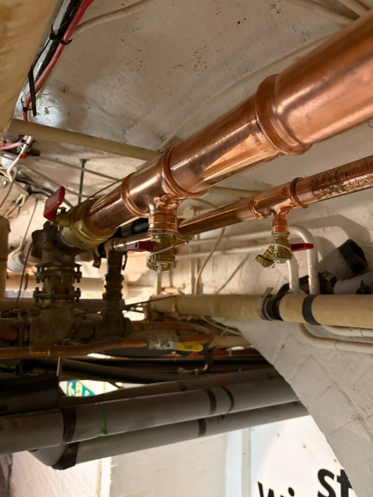 Large-bore copper pipework with isolation and commissioning valves installed at ceiling level