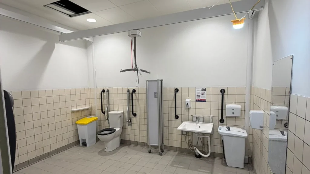 Completed accessible commercial washroom with grab rails, basin and sanitaryware