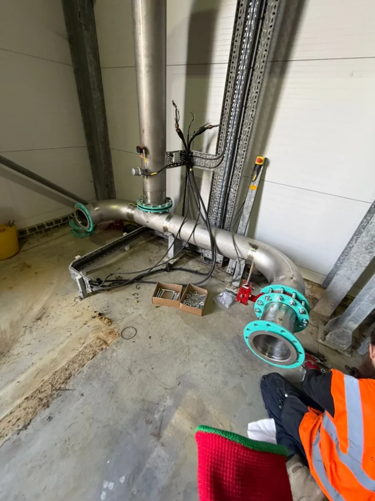 Engineer installing large-bore stainless and ductile pipework in a commercial building