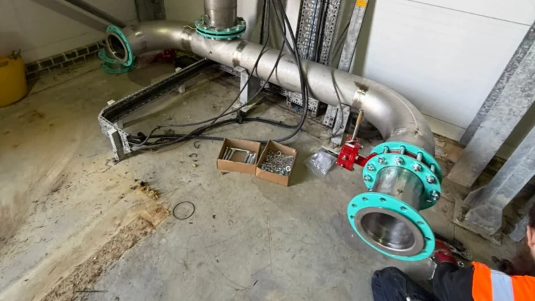 Engineer installing large-bore stainless and ductile pipework in a commercial building