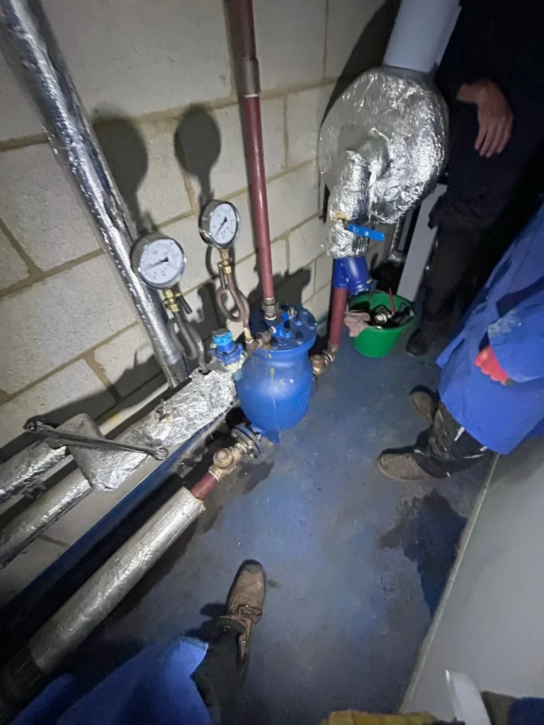 Engineers pressure testing steam pipework with gauges fitted in a plant room