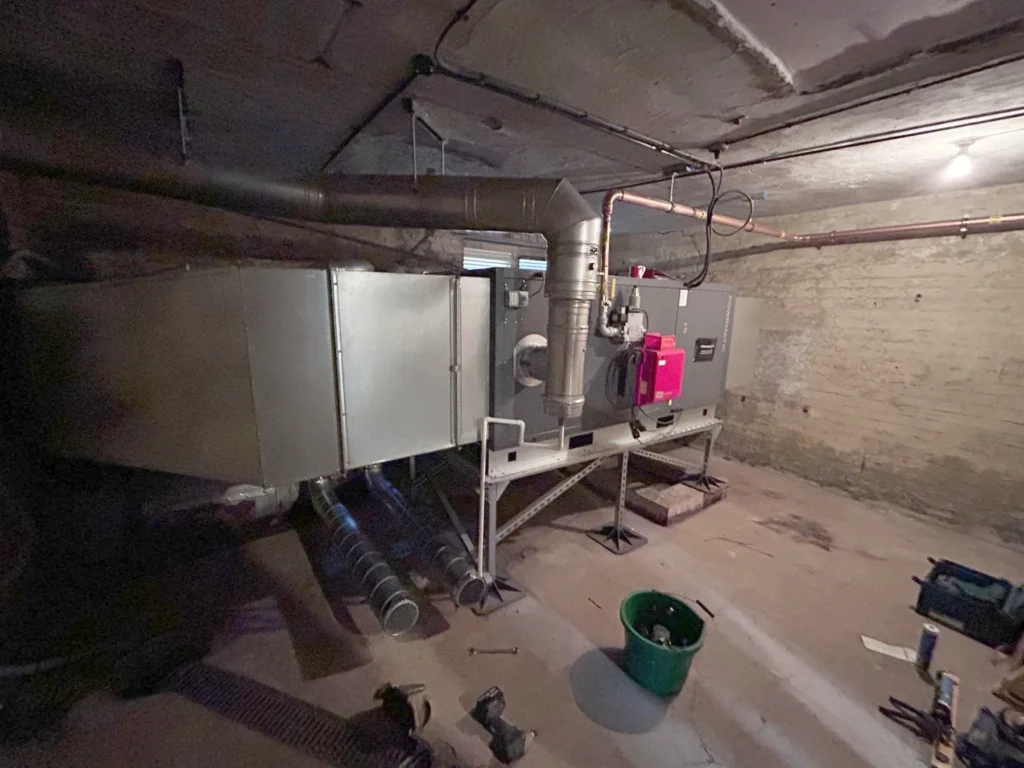 Gas fired warm air heating unit and ductwork installed in a stone walled church basement