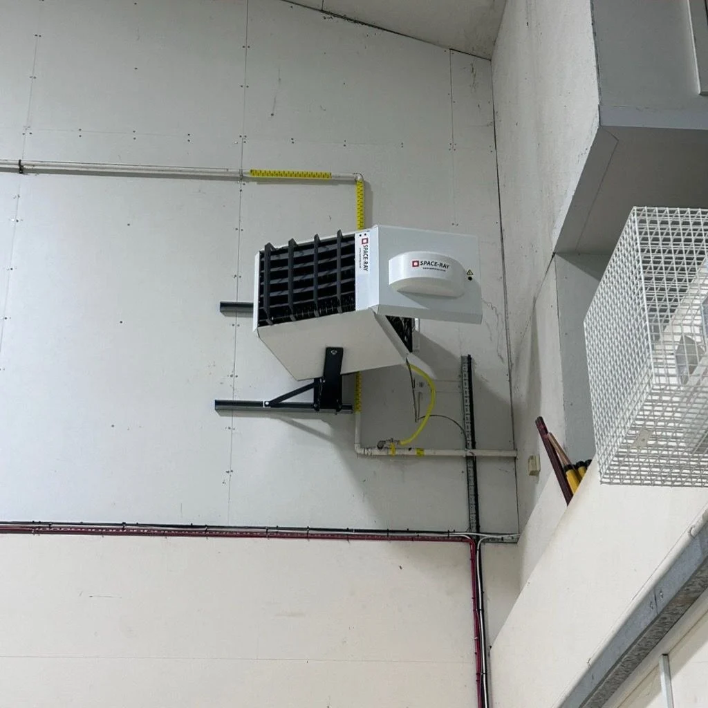 Suspended gas fired warm air unit heater mounted high on a sports hall wall